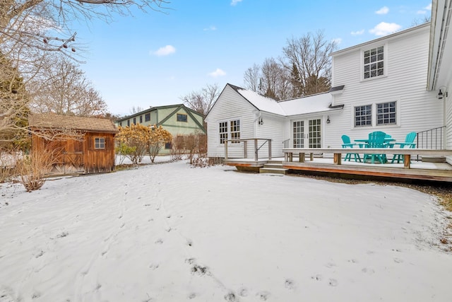 snow covered property with a deck and a storage unit