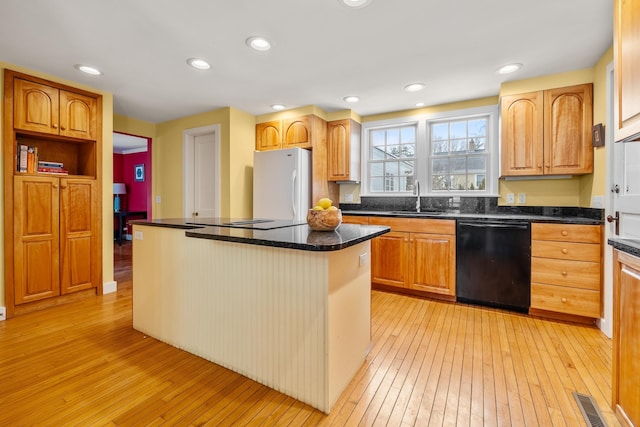 kitchen featuring sink, black appliances, light hardwood / wood-style floors, a kitchen island, and dark stone counters