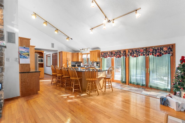 kitchen featuring vaulted ceiling, a textured ceiling, light wood-type flooring, and kitchen peninsula