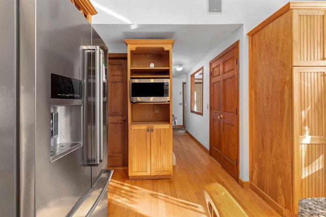 kitchen featuring appliances with stainless steel finishes and light hardwood / wood-style flooring