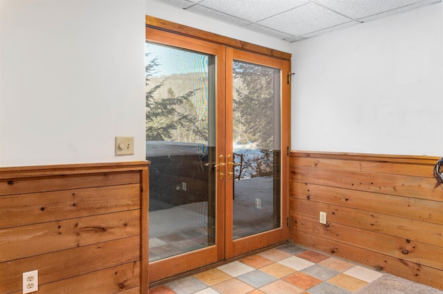 entryway with french doors, a paneled ceiling, and wooden walls