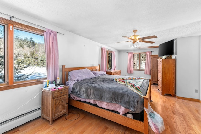 bedroom featuring ceiling fan, light hardwood / wood-style flooring, a textured ceiling, and baseboard heating