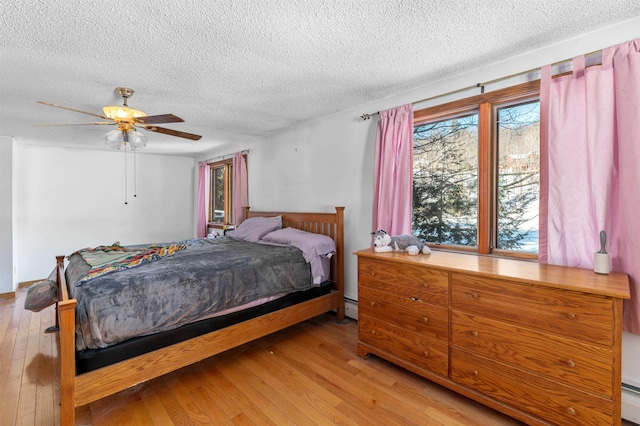 bedroom featuring a baseboard heating unit, hardwood / wood-style floors, and ceiling fan