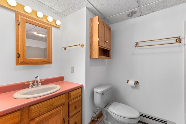 bathroom with baseboard heating, a paneled ceiling, vanity, and toilet