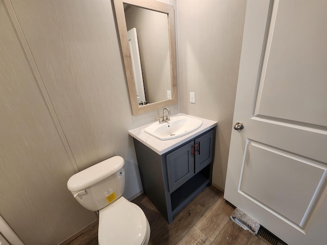 bathroom with hardwood / wood-style flooring, vanity, and toilet