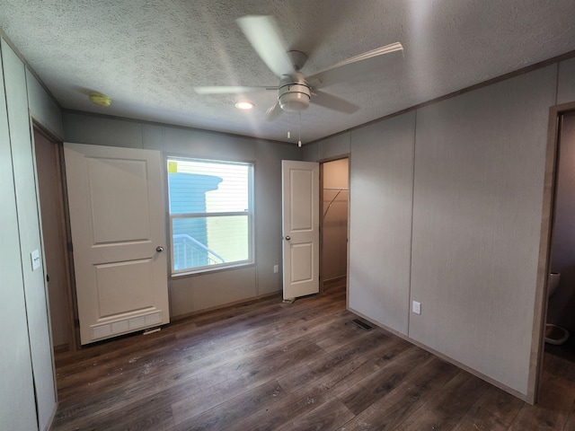 unfurnished bedroom with ceiling fan, dark hardwood / wood-style flooring, a closet, and a textured ceiling