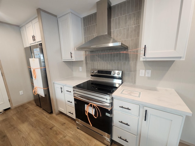 kitchen featuring electric stove, wall chimney exhaust hood, refrigerator, and white cabinets