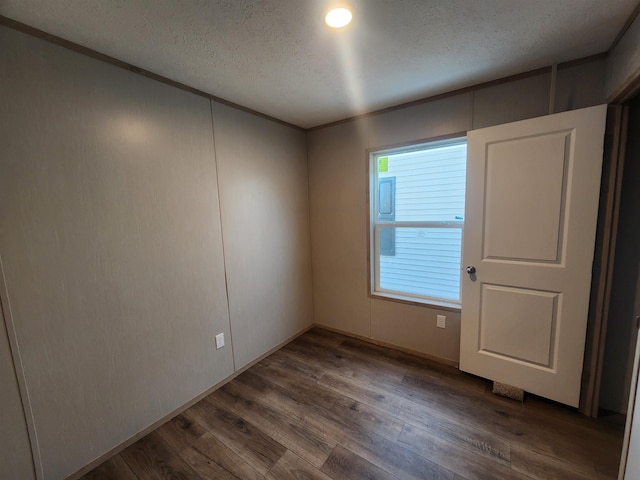 unfurnished room featuring hardwood / wood-style flooring and a textured ceiling