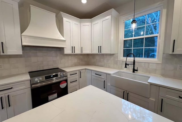 kitchen with premium range hood, a sink, decorative backsplash, stainless steel range with electric cooktop, and pendant lighting