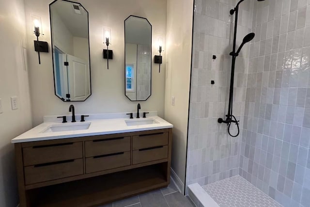 bathroom featuring a sink, double vanity, and a tile shower