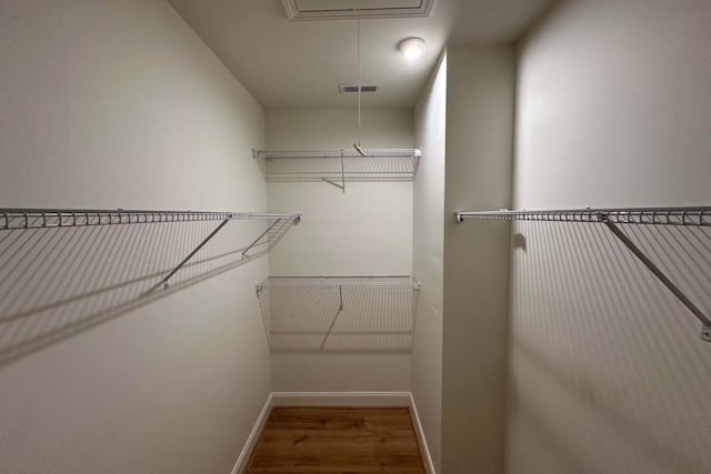 walk in closet featuring visible vents, attic access, and wood finished floors