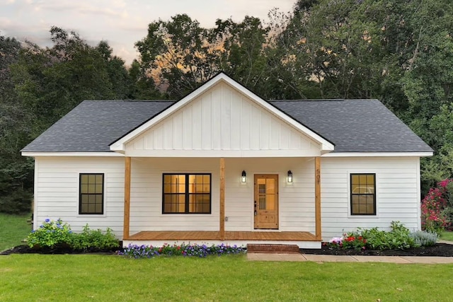 modern inspired farmhouse featuring a porch, a shingled roof, a yard, and board and batten siding