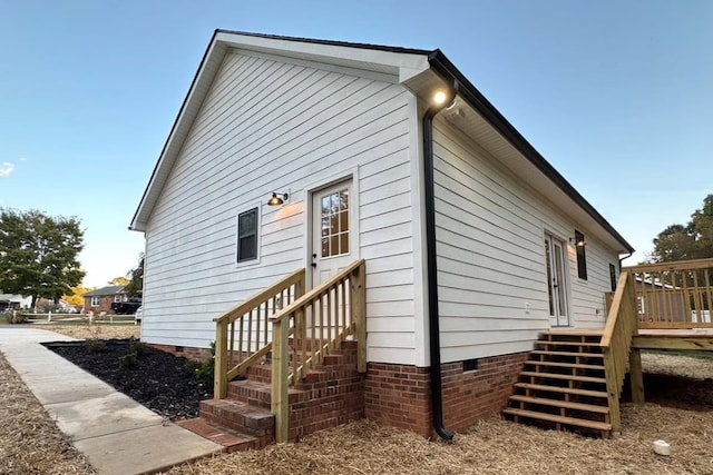 view of side of property with crawl space, entry steps, and a wooden deck