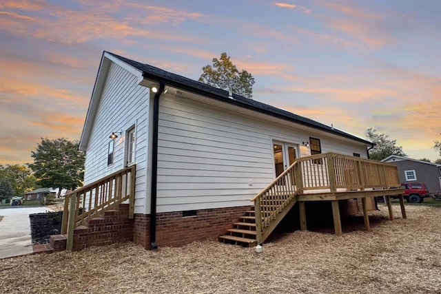 back of property at dusk with stairs, a deck, and crawl space