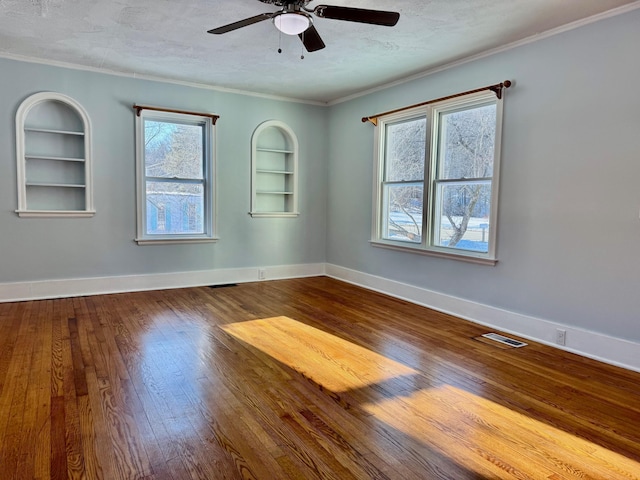 unfurnished room featuring built in shelves, crown molding, a textured ceiling, and hardwood / wood-style flooring