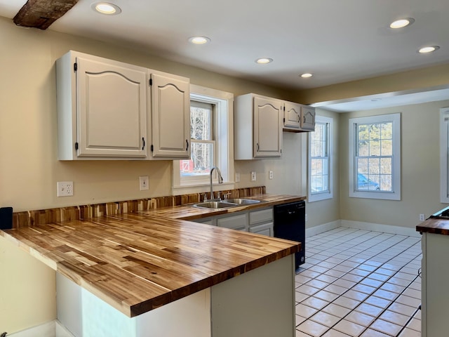 kitchen featuring sink, light tile patterned floors, butcher block counters, black dishwasher, and white cabinets