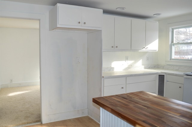 kitchen with baseboards, white cabinets, and light colored carpet