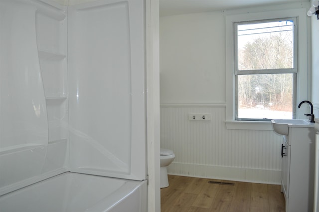 bathroom featuring a wainscoted wall, plenty of natural light, wood finished floors, and visible vents