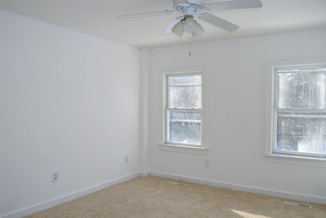 unfurnished room featuring light colored carpet, visible vents, ceiling fan, and baseboards