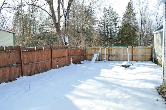 snowy yard with a fenced backyard