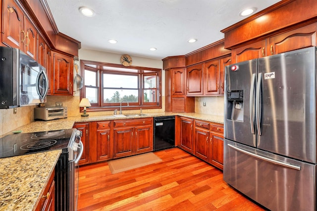 kitchen featuring light wood-type flooring, sink, stainless steel appliances, and light stone counters