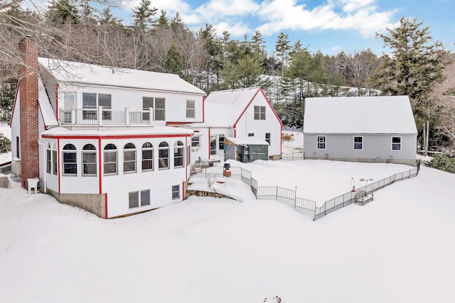 snow covered back of property featuring a balcony