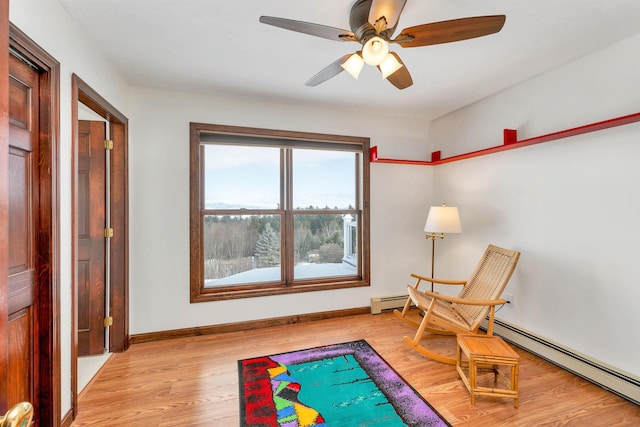 sitting room with ceiling fan, light hardwood / wood-style flooring, and a baseboard heating unit