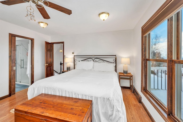 bedroom with light hardwood / wood-style floors, baseboard heating, and ensuite bath