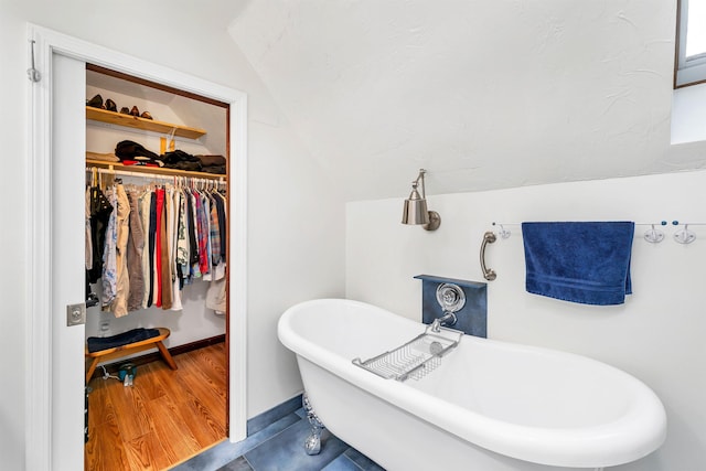 bathroom with hardwood / wood-style floors, a washtub, and lofted ceiling