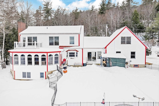 snow covered back of property with a balcony