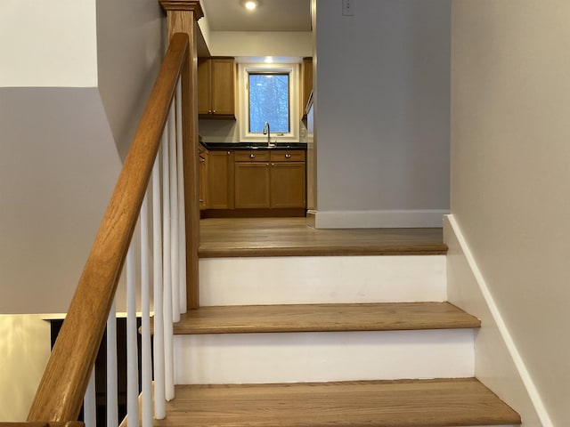 stairway featuring hardwood / wood-style flooring and sink