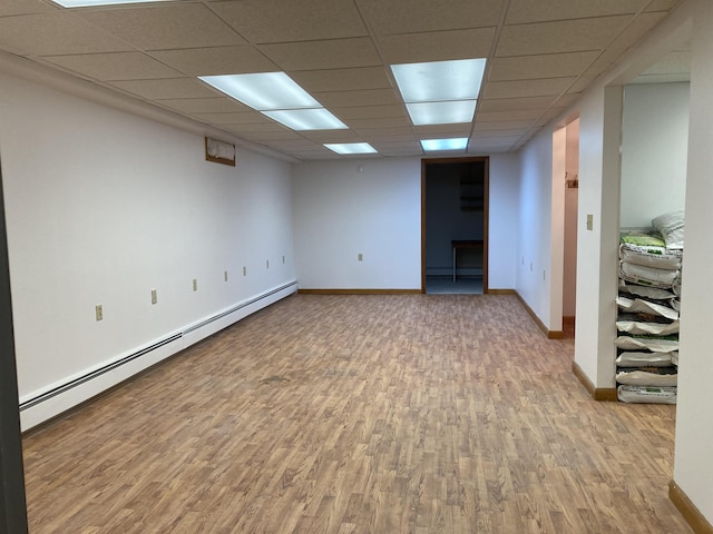 basement with hardwood / wood-style flooring, a paneled ceiling, and baseboard heating