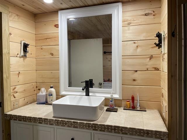 bathroom featuring vanity, wood ceiling, and wood walls