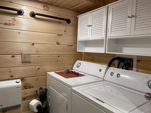 laundry room featuring wood ceiling, washer and clothes dryer, and wood walls