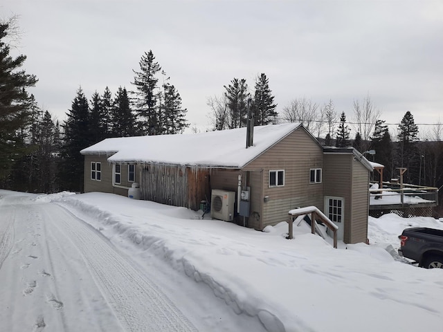 snow covered house featuring ac unit