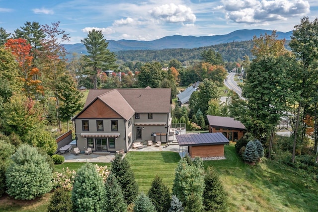 exterior space featuring a mountain view, a lawn, and a patio area