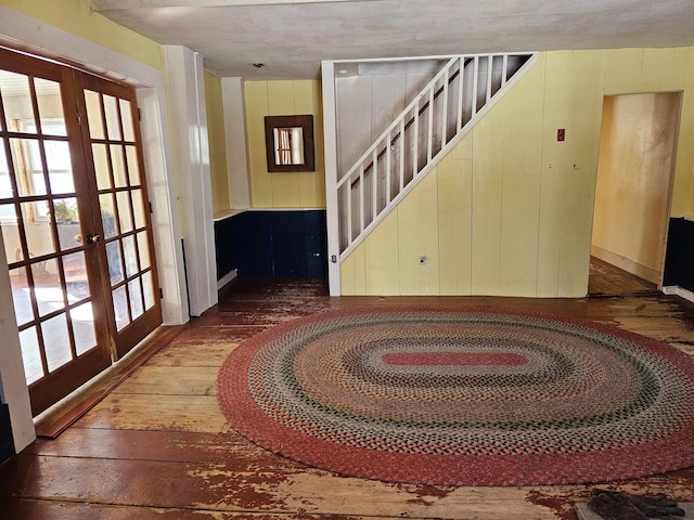 entryway featuring dark hardwood / wood-style floors, wood walls, and french doors