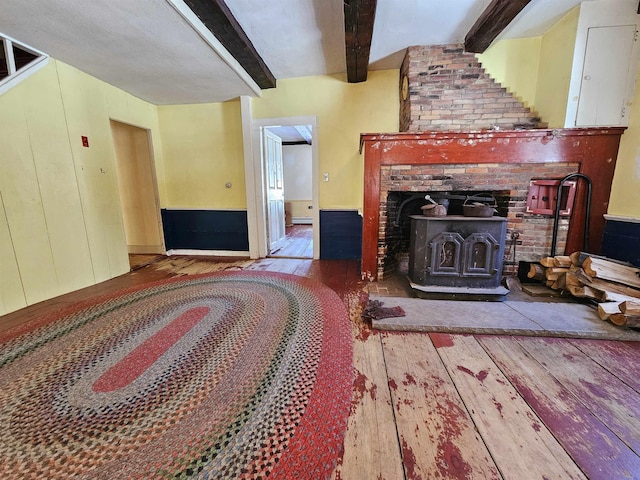 living room with beamed ceiling, wood-type flooring, and a wood stove