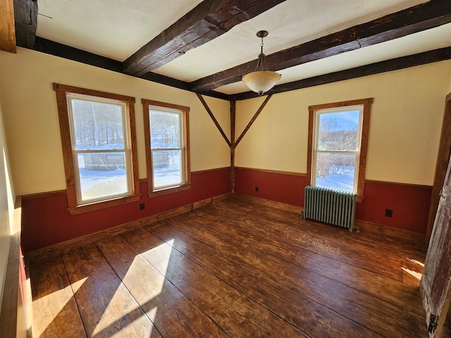 empty room featuring dark wood-type flooring, radiator, and beamed ceiling