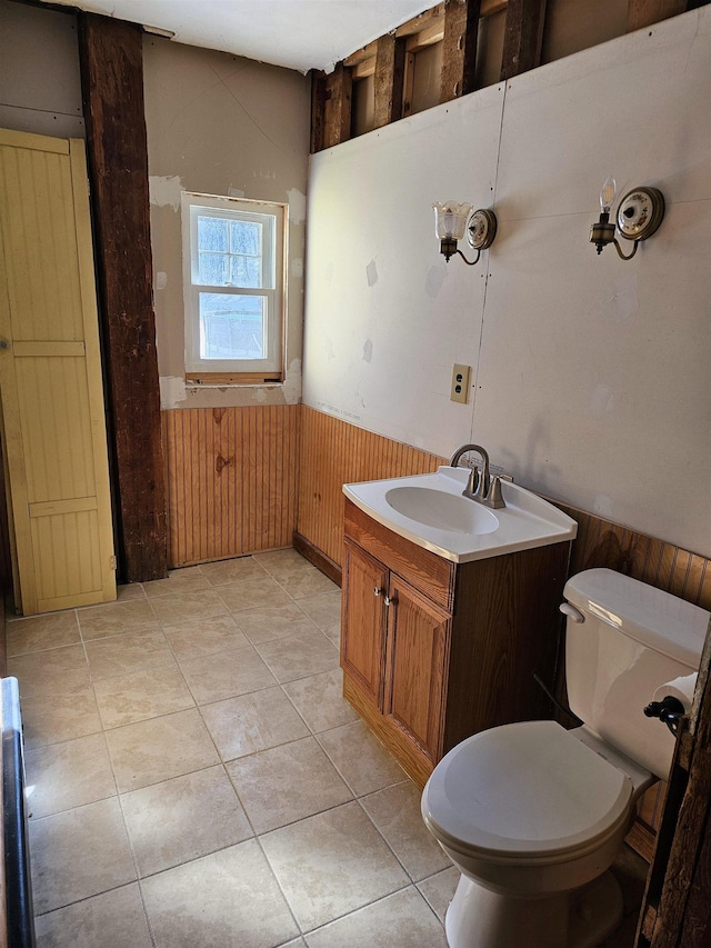 bathroom featuring vanity, tile patterned flooring, toilet, and wood walls