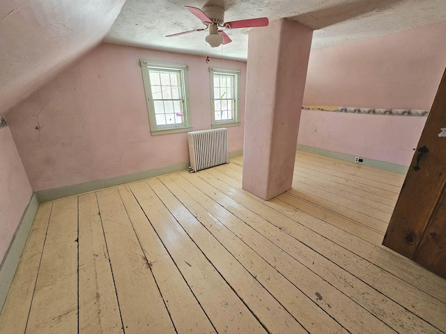 bonus room with radiator, lofted ceiling, ceiling fan, a textured ceiling, and light hardwood / wood-style flooring