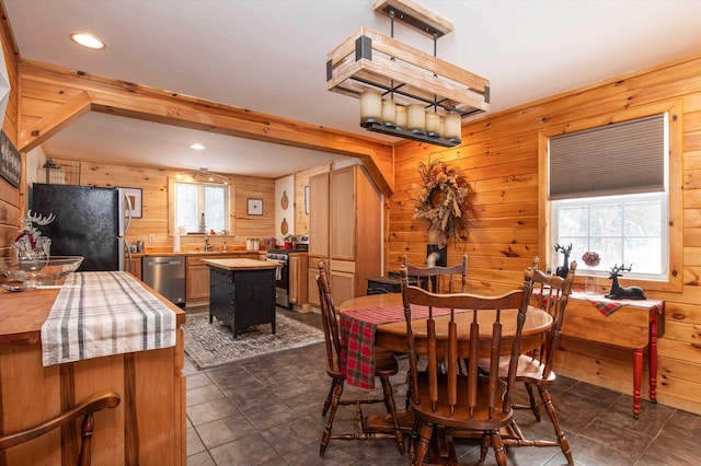 dining space featuring beamed ceiling, sink, and wooden walls