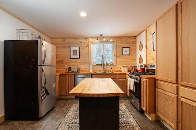 kitchen with sink, butcher block counters, stainless steel appliances, a center island, and ornamental molding