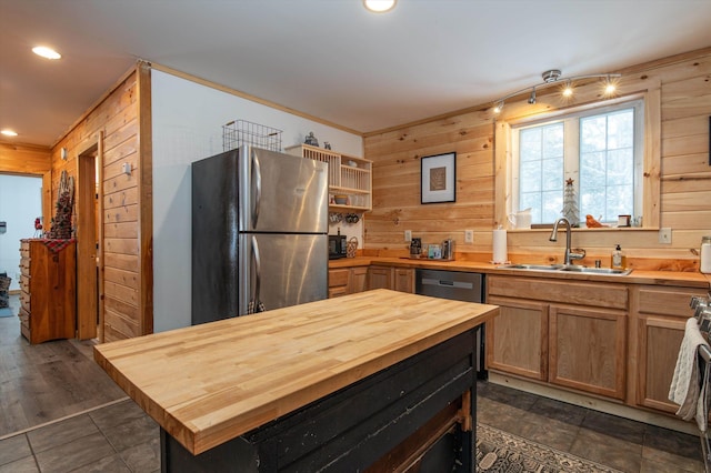 kitchen with wooden walls, stainless steel fridge, butcher block counters, and sink