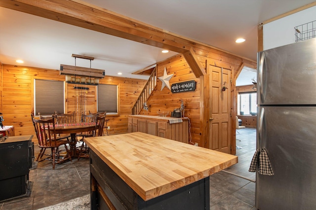 kitchen featuring wooden walls, stainless steel refrigerator, wooden counters, and a center island