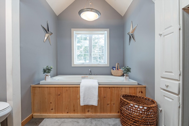 bathroom featuring lofted ceiling, a washtub, and toilet