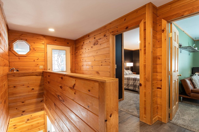 hall with wood-type flooring and wooden walls