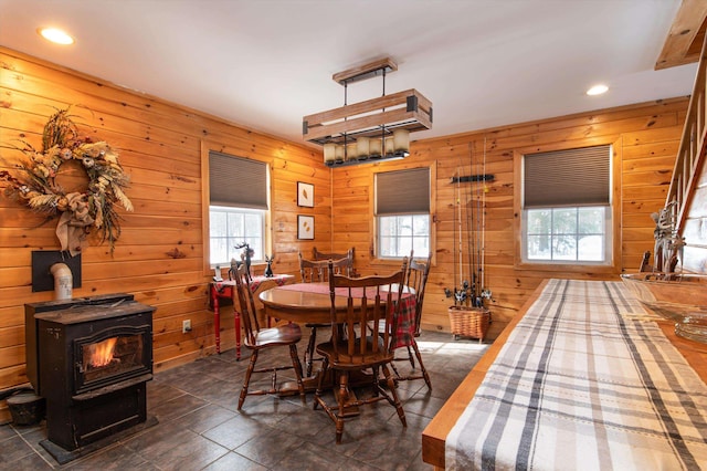 dining area with a healthy amount of sunlight, wooden walls, and a wood stove