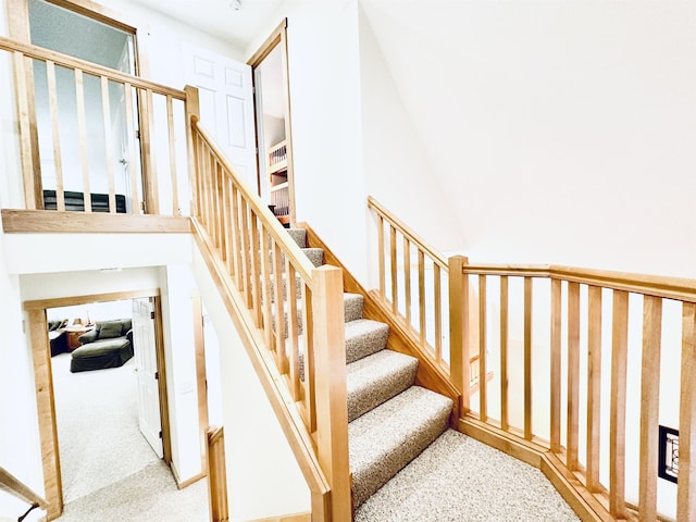 staircase featuring carpet