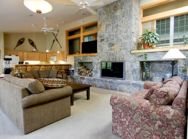 living room featuring carpet floors, a towering ceiling, a fireplace, and ceiling fan